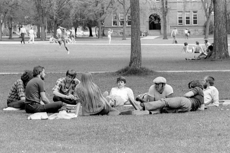 University of Montana students gather in the Oval with Main Hall in the background in the 1970s. (Mansfield Library, University of Montana)