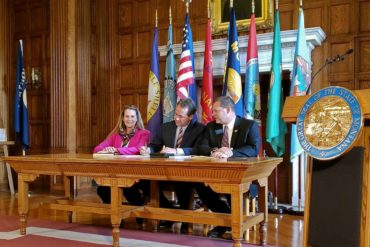 Democratic Rep. Mary Caferro, left, and Republican Rep. Ed Buttrey, right, look on as Gov. Steve Bullock signs House Bill 658, reauthorizing Montana’s Medicaid expansion program. (AP Photo, Amy Beth Hanson)