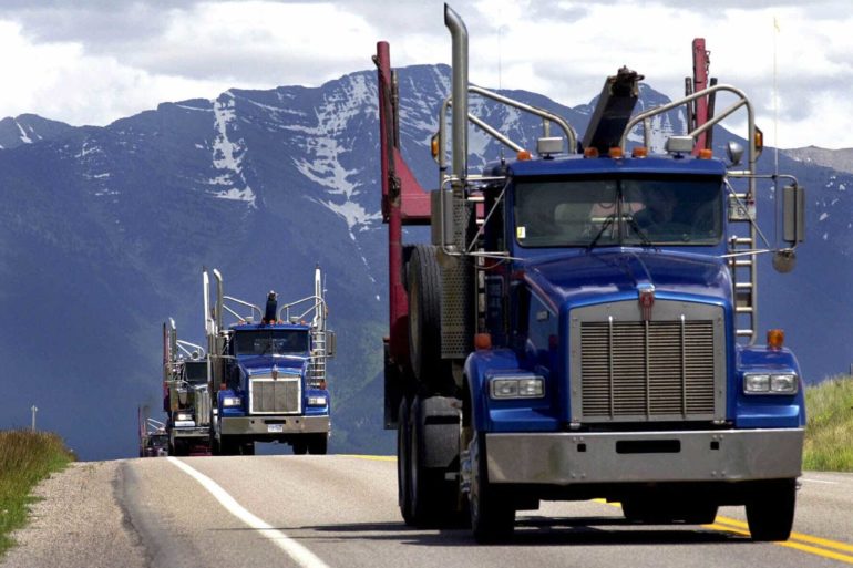 A convoy of log trucks head south on U.S. Highway 93. (AP Photo, Kurt Wilson)