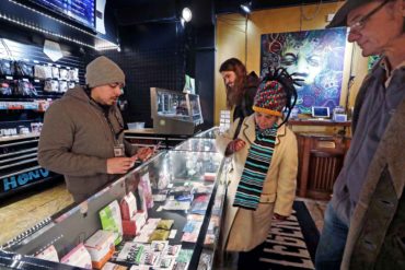 Cannabis consultant Juan Aguilar assists customers shopping for cannabis products in the Herban Legends store in Seattle. (AP Photo, Elaine Thompson)