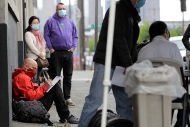 Glen Buhlmann, lower left, fills out a job application during a walk- and drive-up job fair in Seattle. (AP Photo, Ted S. Warren)