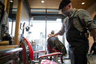 Bryan Kirkland takes extra time to clean between clients at The Barbershop and Shaving Parlor in Bozeman. (AP Photo, Ryan Berry)