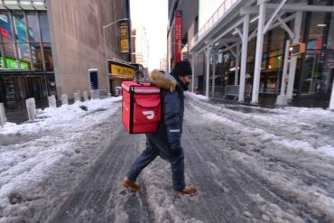 A DoorDash food delivery person makes his way through slushy snow in New York City during a second wave of the COVID-19 pandemic. (AP Photo, Anthony Behar)